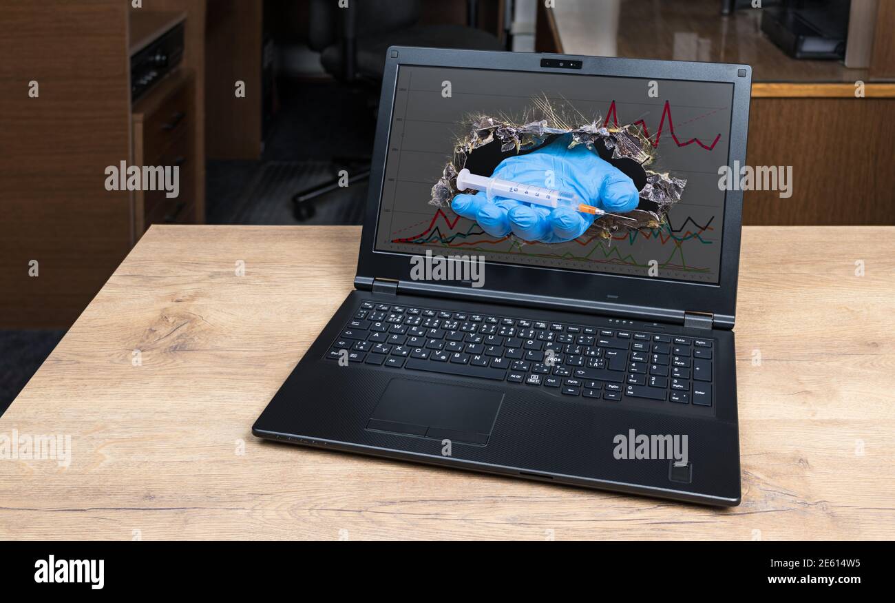 Mano d'aiuto con la siringa che sporge dal foro nello schermo rotto del laptop con il grafico covid-19. Medico virtuale simbolico. Speranza del vaccino della malattia del coronavirus. Foto Stock