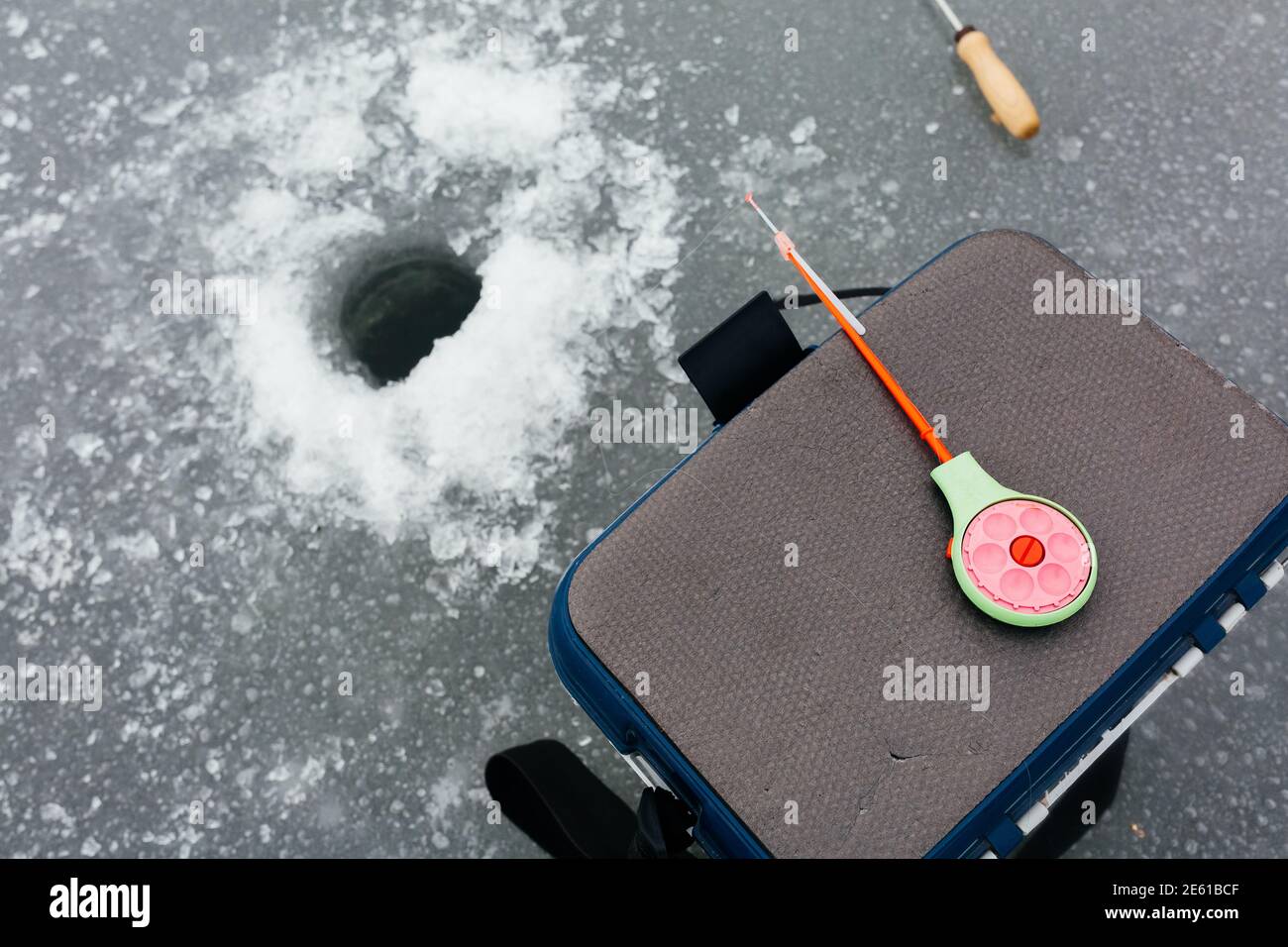 Primo piano attrezzatura per la pesca sul ghiaccio e attrezzature vicino al buco del ghiaccio. Concetto di pesca invernale. Pesca sul ghiaccio Foto Stock