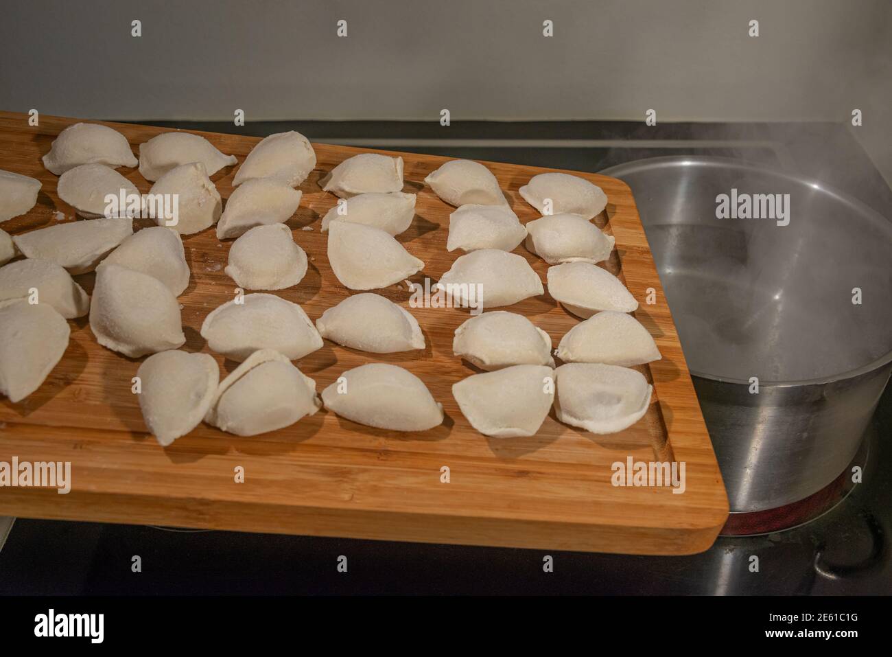 Cottura di gnocchi con carne bollendo in acqua in una padella, gnocchi surgelati raccolti in piastra di legno e pronti per il carico, dettagli, chiocchetti. Foto Stock