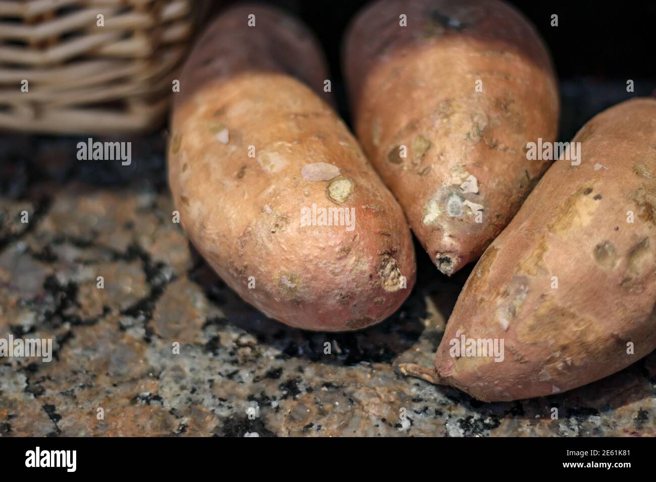 Tre patate dolci si vedono da vicino su un piano di granito. Foto Stock