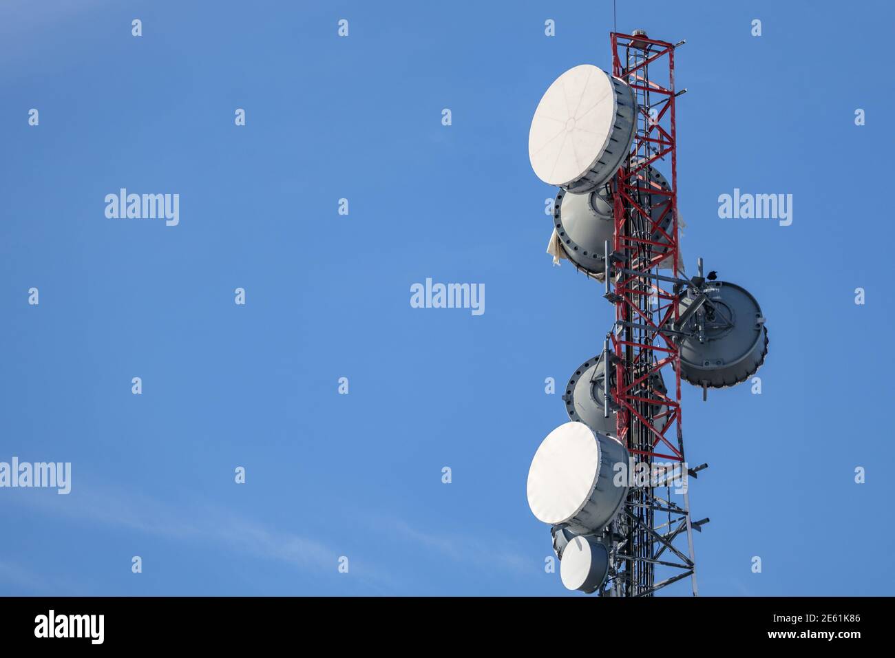La parte superiore di una torre di comunicazione contiene una serie di diverse antenne backhaul a microonde con coperture protettive per radome, dando loro l'appeas Foto Stock