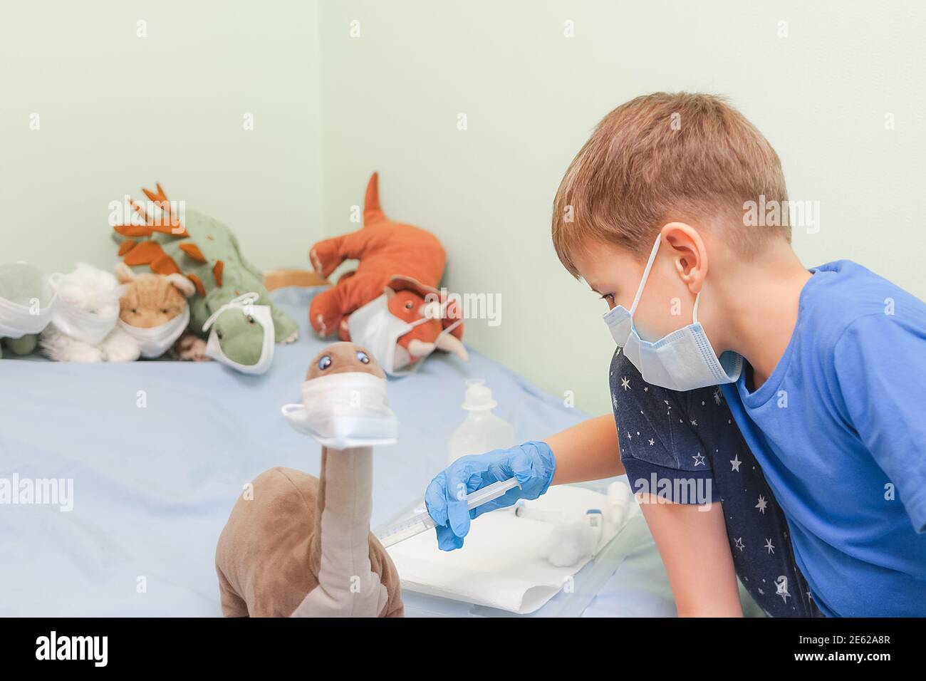 Il bambino gioca a giochi di ruolo. Il piccolo medico vaccina il giocattolo del paziente Boy tratta il dinosauro Foto Stock