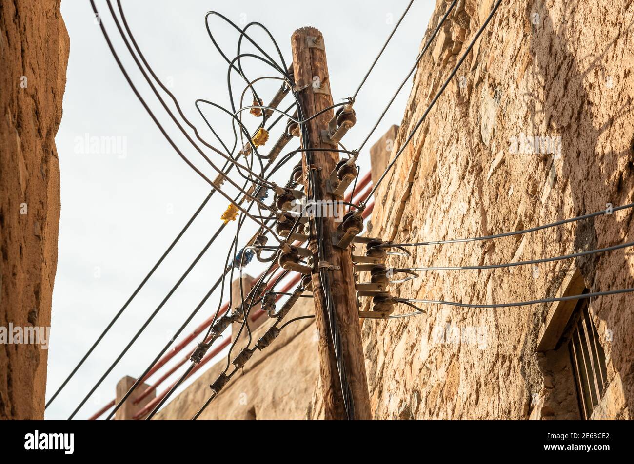 Cavi elettrici sul pilastro elettrico in legno nel vecchio villaggio di montagna Migrat al Abriyeen nel Sultanato dell'Oman. Foto Stock