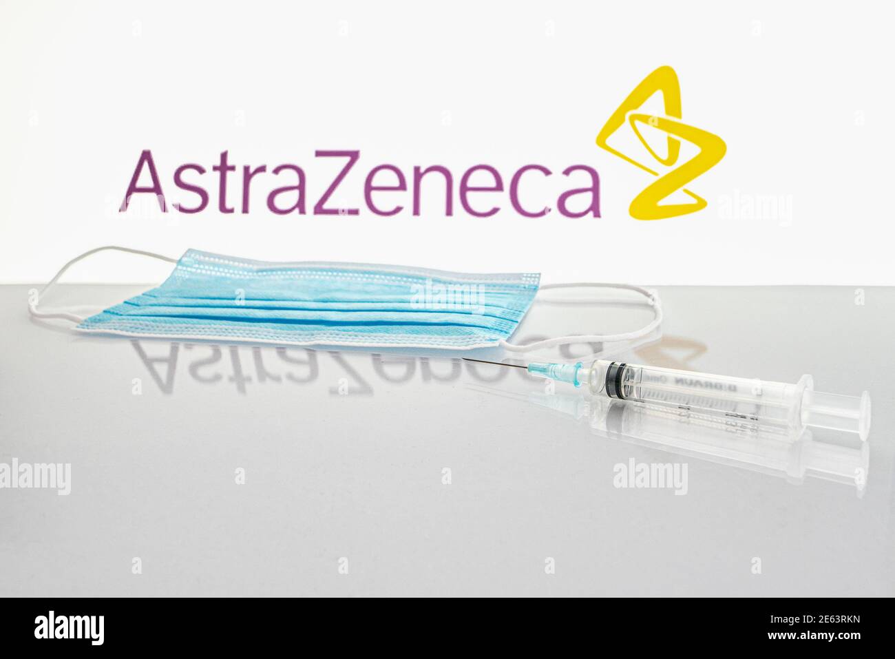 Siringa e maschera facciale su un tavolo davanti al logo AstraZeneca, Danimarca, 28 gennaio 2021 Foto Stock