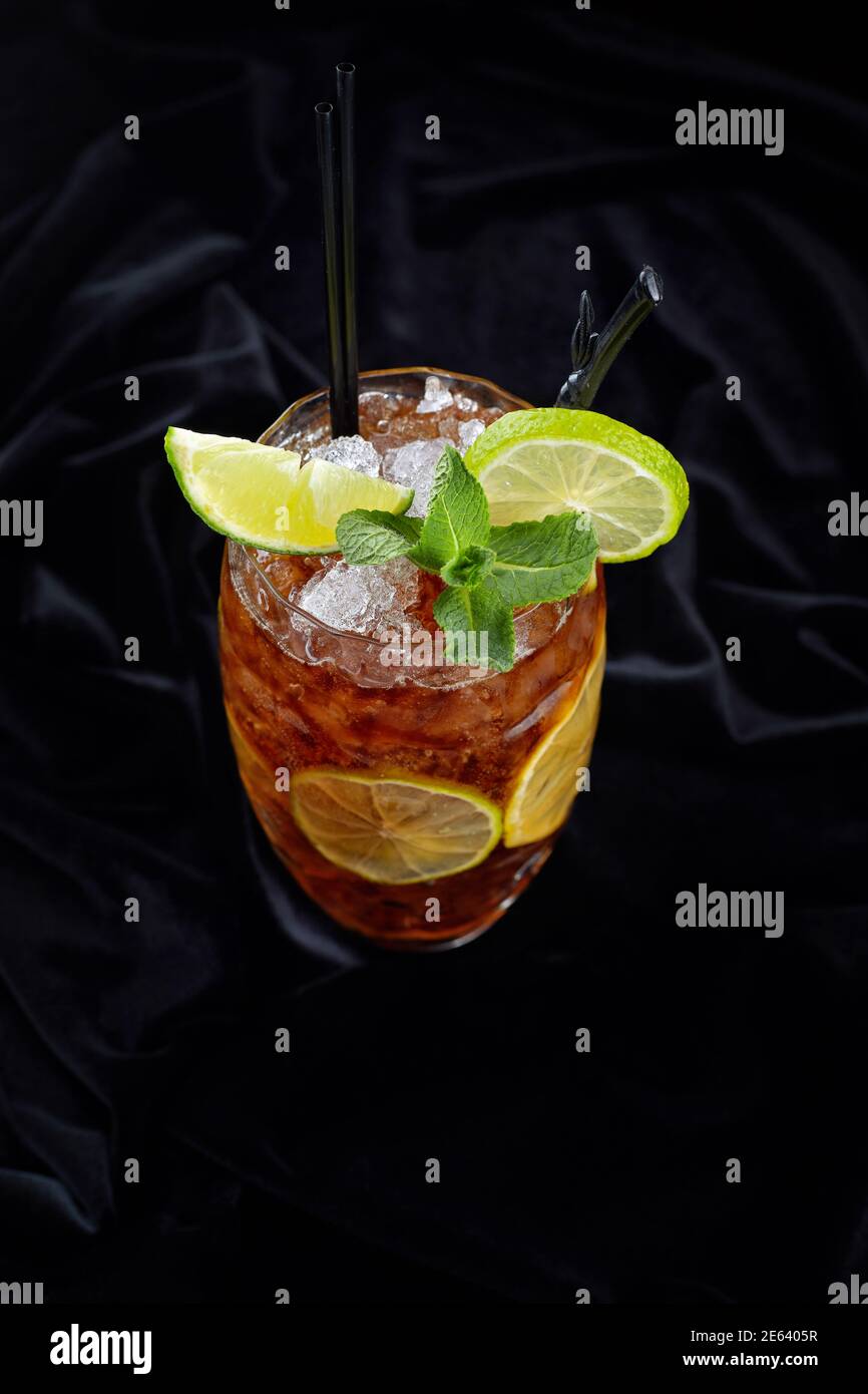 Cocktail alcolico, Long Island Ice Tee, su velluto nero, su sfondo nero con lime e menta Foto Stock