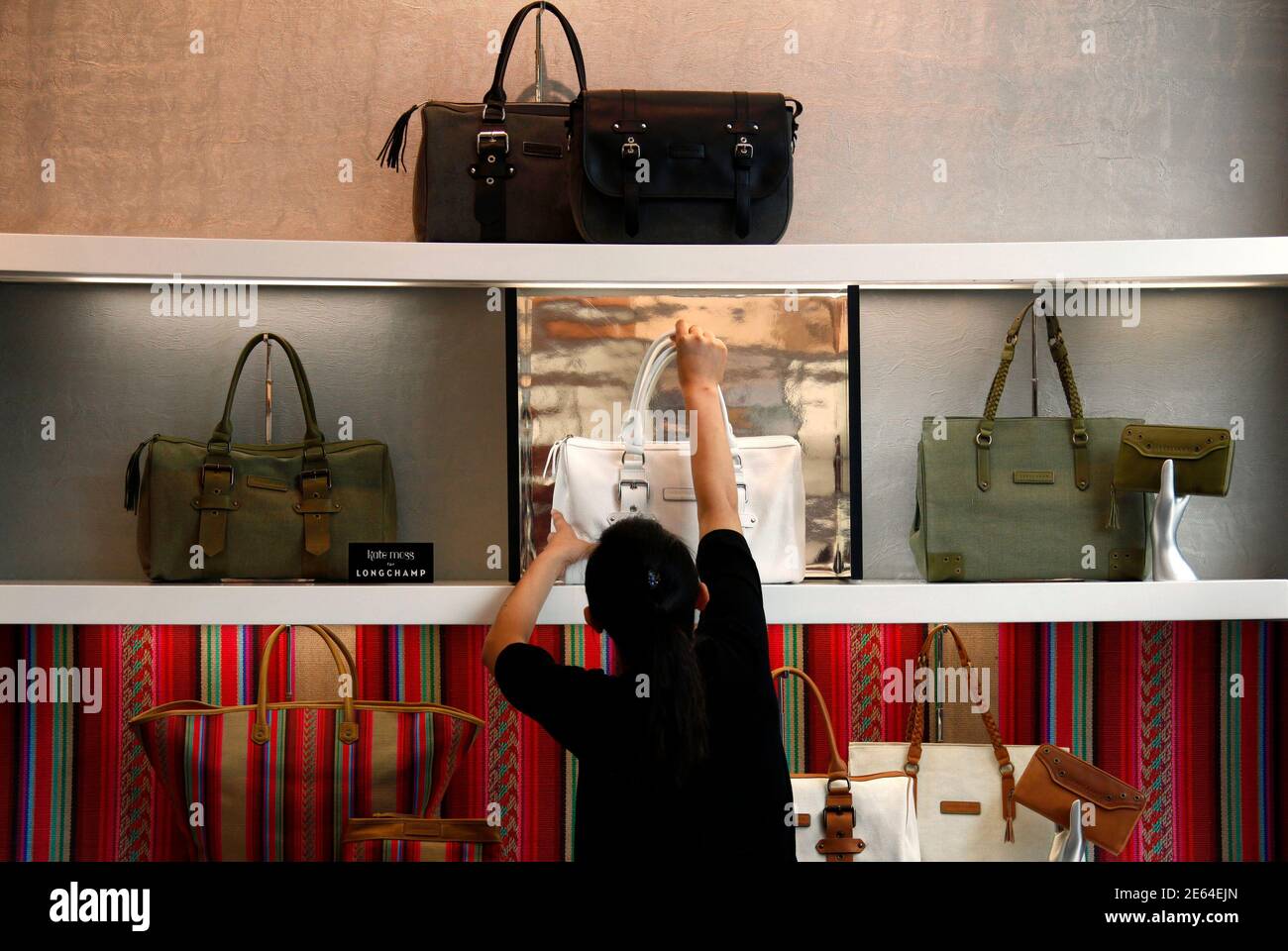 Un lavoratore in un negozio per il produttore francese di beni di lusso  Longchamp regola una visualizzazione di borse che sono promosse dal modello  britannico Kate Moss nel centro di Pechino 6