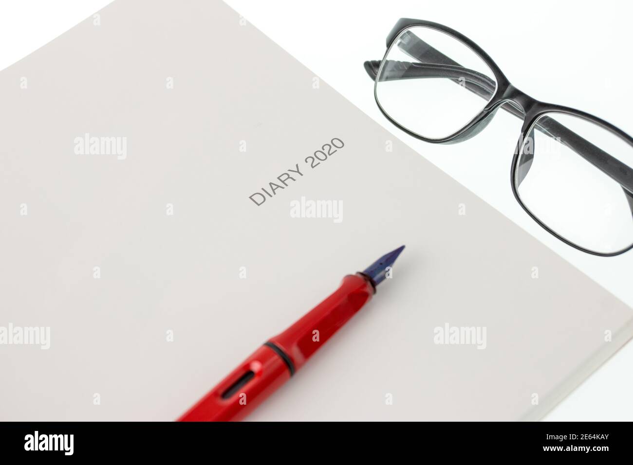 diario 2020, penna e bicchieri su sfondo bianco Foto Stock