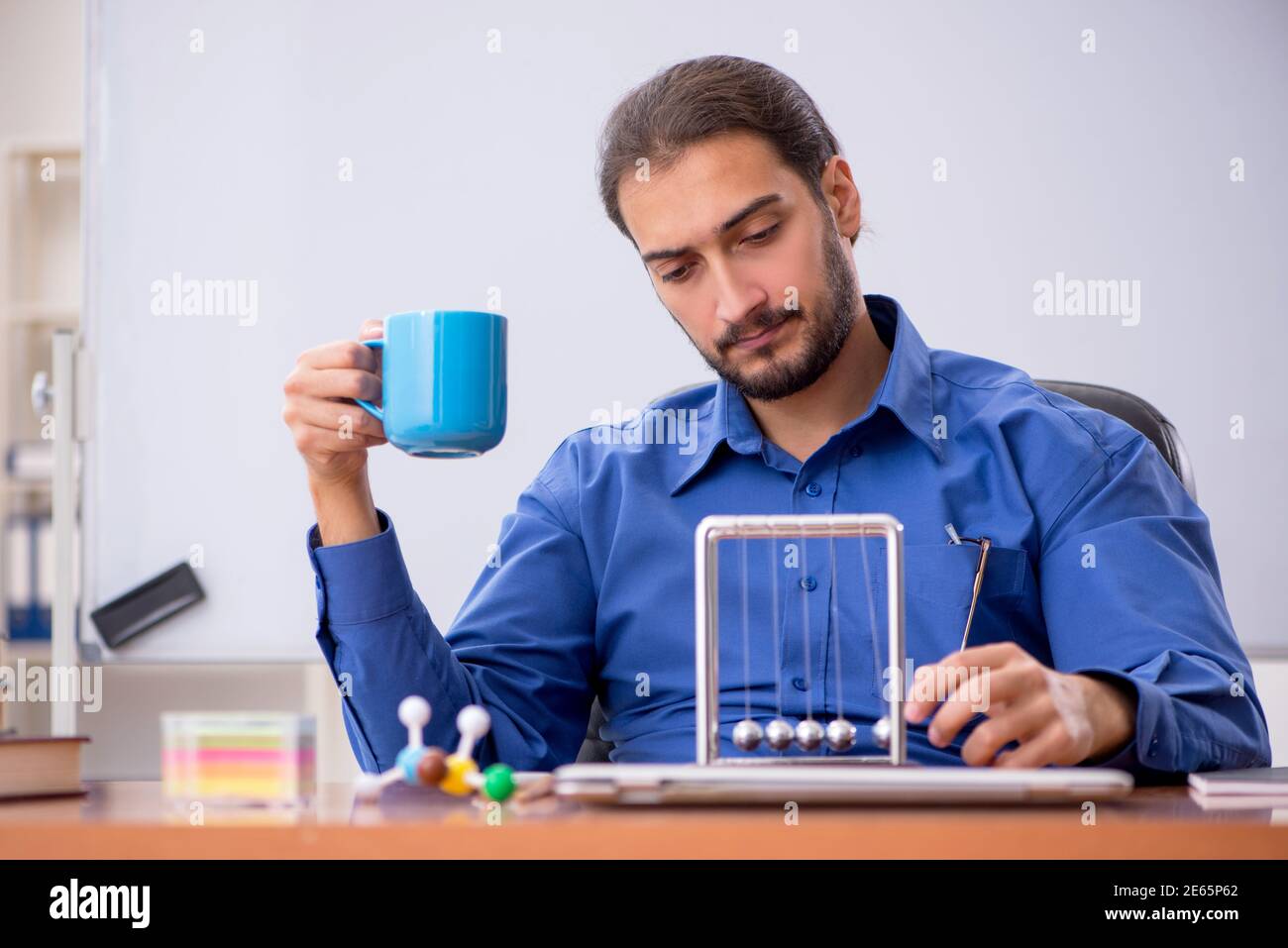 Fisico di un giovane insegnante seduto in classe Foto Stock