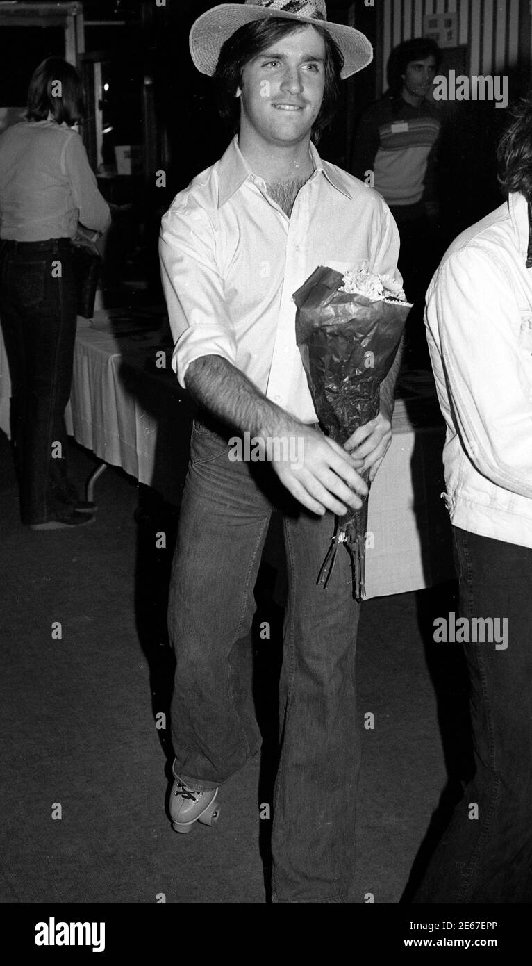 Uomo su pattini a rotelle con bouquet di fiori a rullo rink a Los Angels, California, circa anni '70 Foto Stock