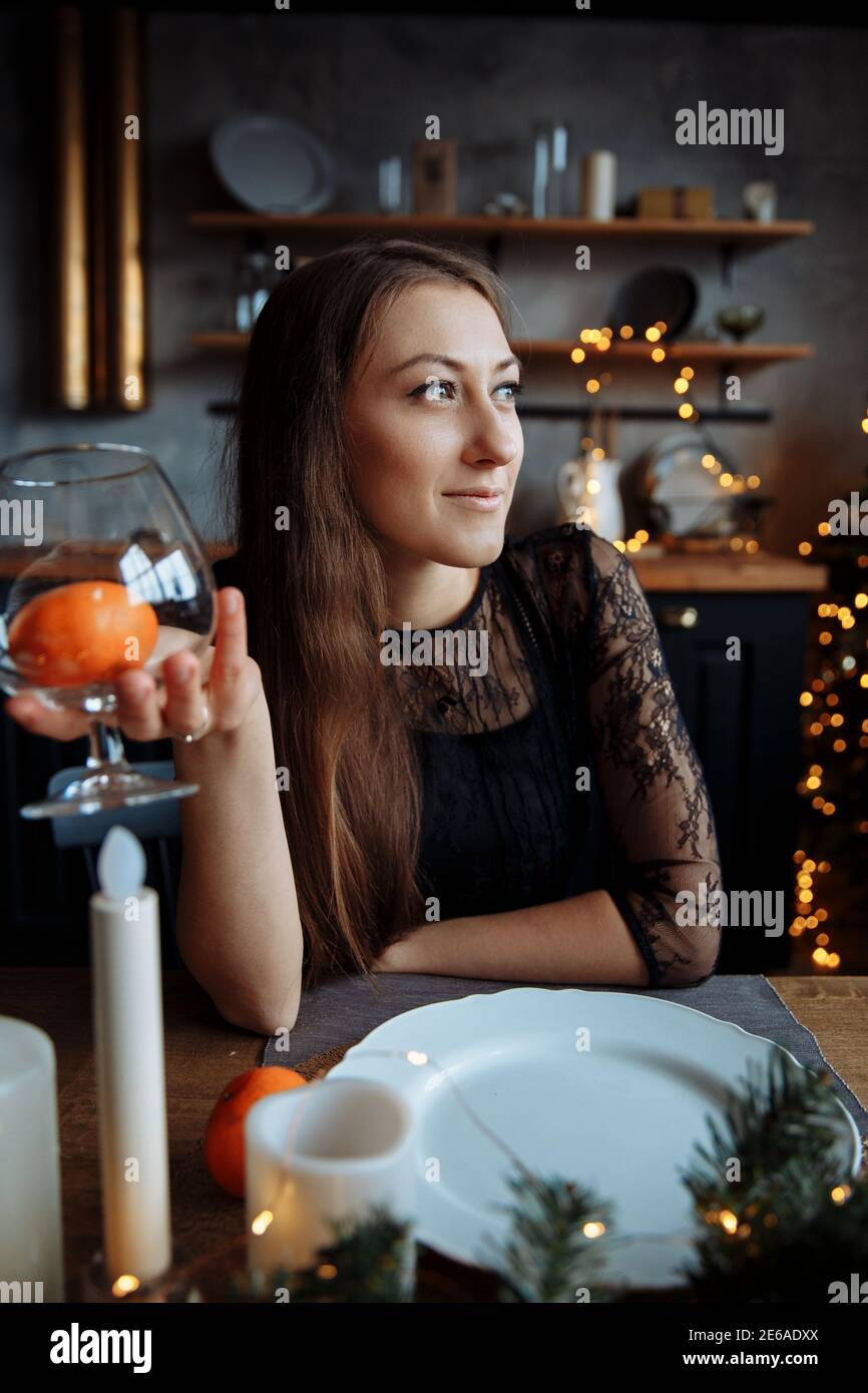 Una bella giovane donna in un vestito nero si siede al tavolo e tiene una drogheria. Foto Stock