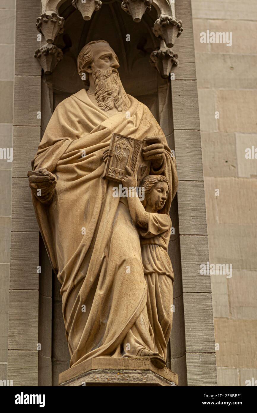 Antica statua di San Lorenzo tenendo una bibbia in mano con un bambino accanto a lui, all'angolo di San Laurenzen Kirche (St Lawrence Church) un istore Foto Stock