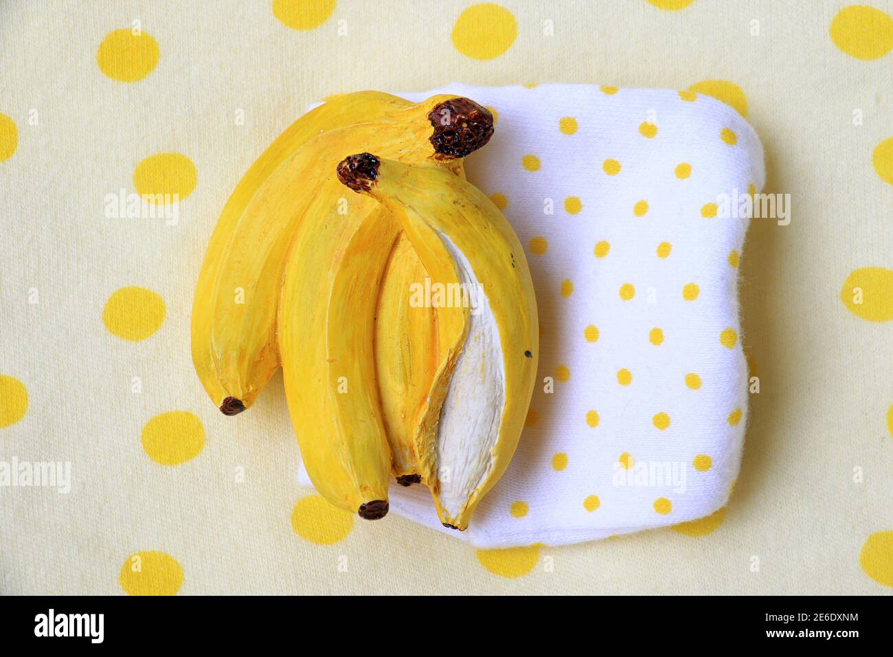 Una miniatura in resina di banana su uno sfondo da picnic punteggiato. Foto Stock