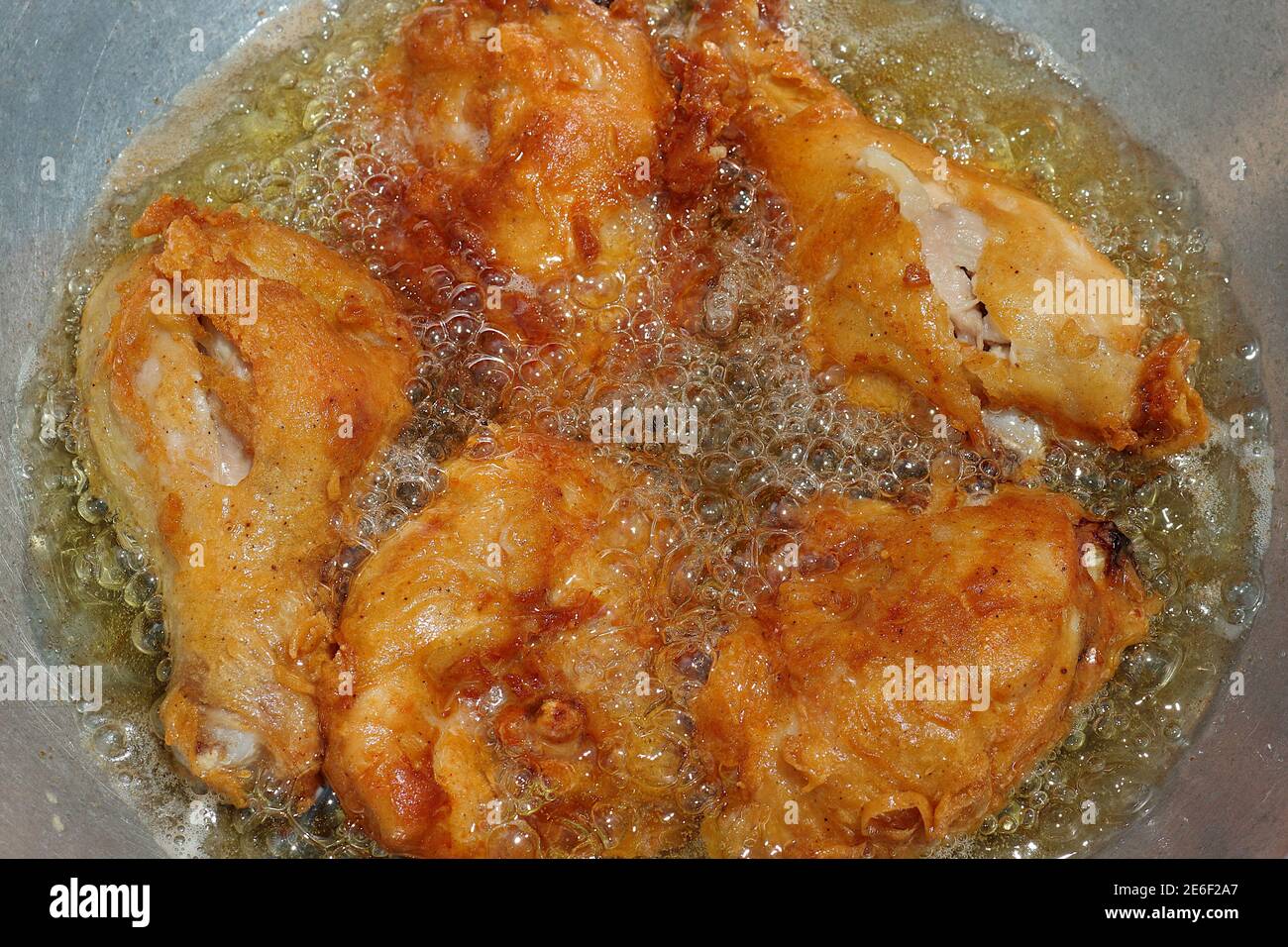 I pezzi di pollo vengono fritti in una padella di olio bollente. È giallo dorato da mangiare. Foto Stock