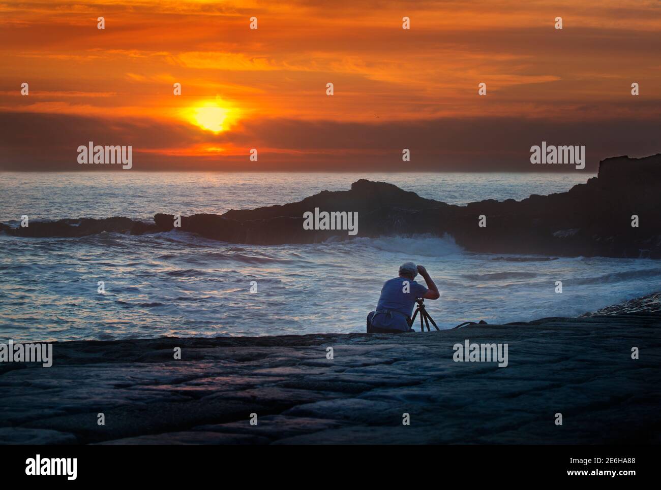 Un fotografo che scatta foto al tramonto su una spiaggia della Cornovaglia, Bude, Cornovaglia, Regno Unito Foto Stock