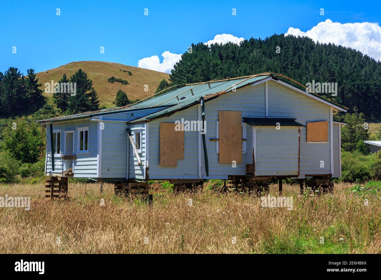 Una casa vuota con finestre a bordo in campagna, appese su blocchi per la rimozione. Fotografato in Nuova Zelanda Foto Stock