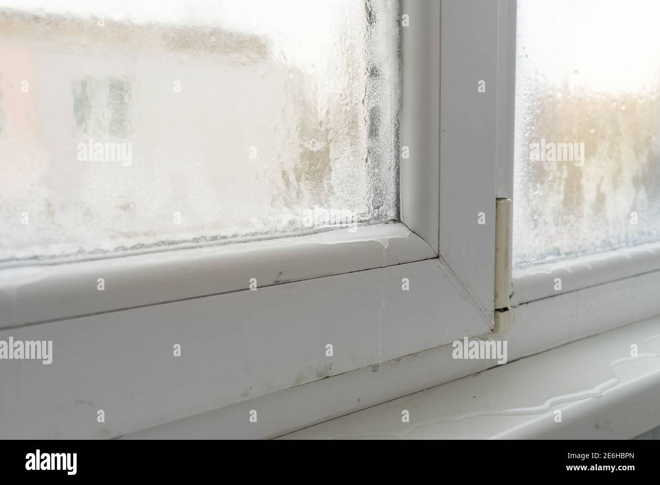 Primo piano di una finestra in plastica difettosa con condensa e congelamento all'interno. Scarsa ventilazione, elevata umidità e differenze di temperatura. Foto Stock