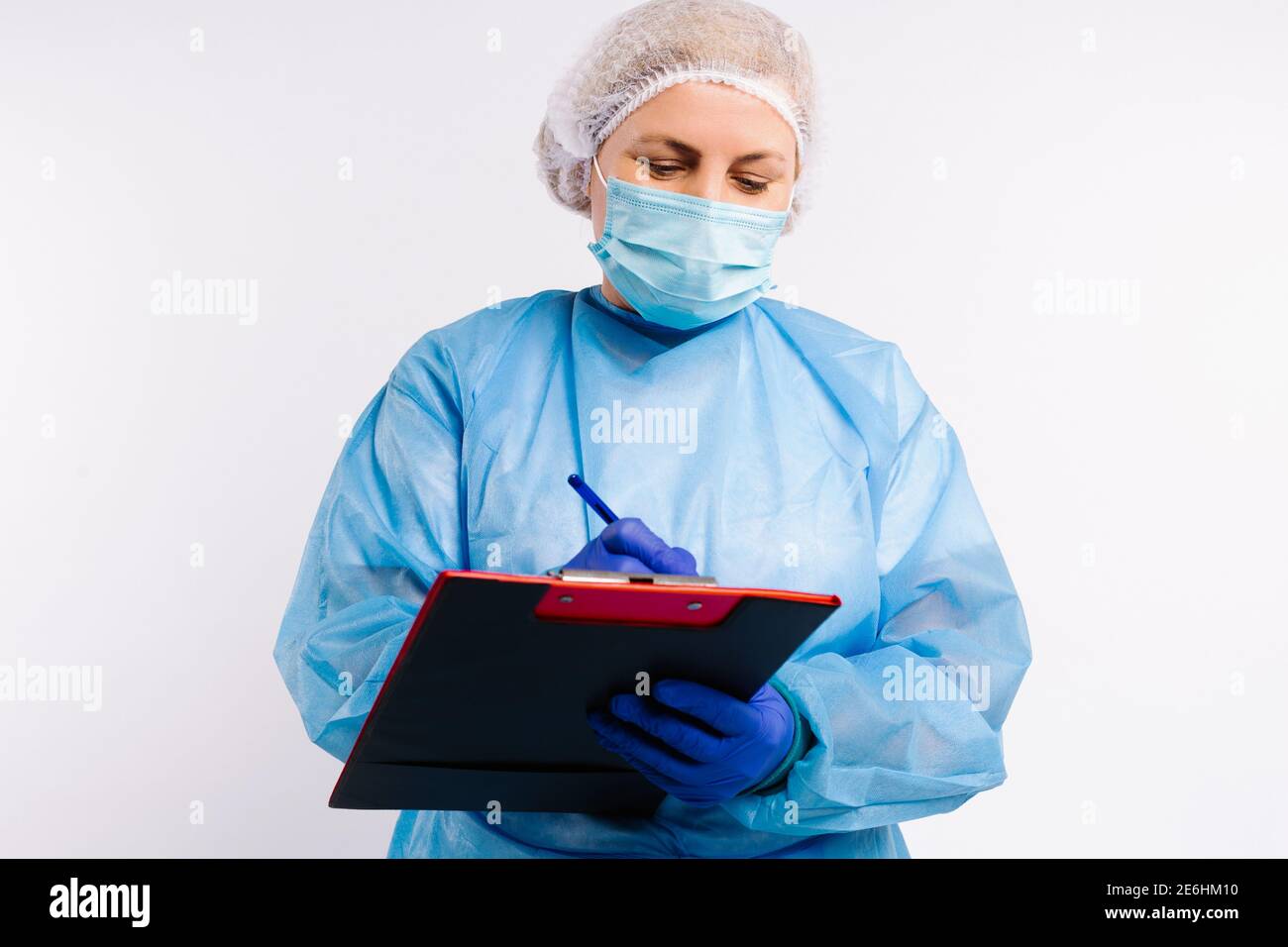 Un medico in apparecchiature mediche di protezione contro l'infezione da covid 19 che compila gli elenchi dei pazienti su uno sfondo bianco. Foto Stock