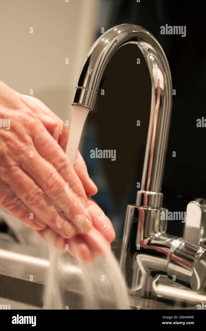 Primo piano, di persona che lavano le mani con sapone sotto il rubinetto dell'acqua in un ambiente moderno del bagno. Concetto di igiene. Messa a fuoco selettiva e immagine tiltet wi Foto Stock