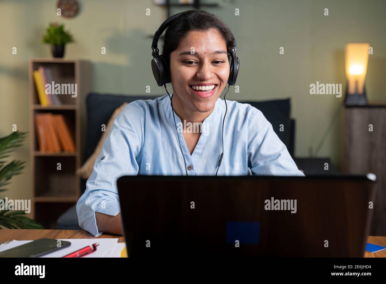 Felice sorridente giovane donna d'affari con cuffie in videochiamata su portatile occupato parlare - concetto di chat online, webinar a distanza, video conferenza du Foto Stock