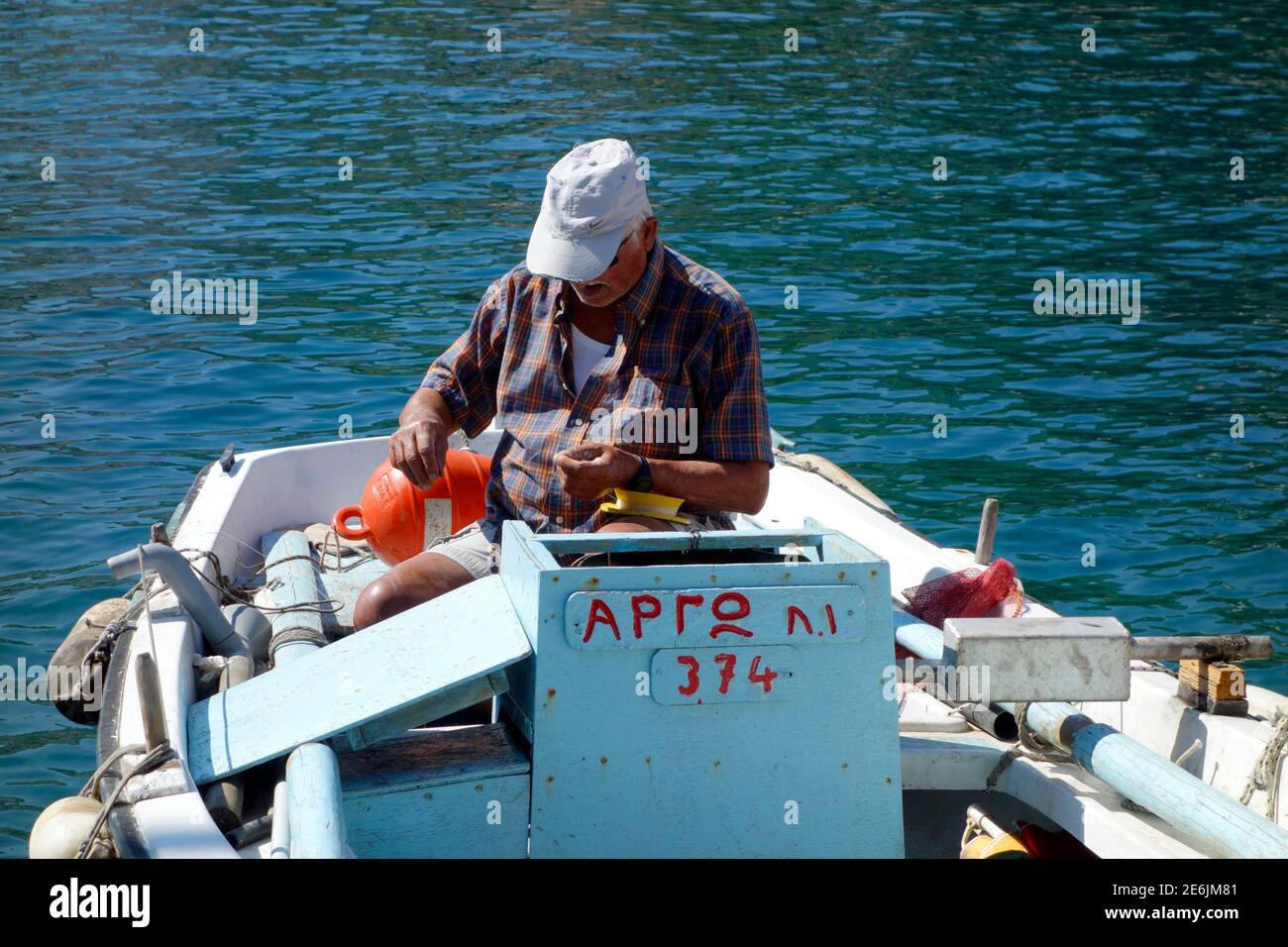 Un pescatore greco si snoda su una barca nel porto di Kioni, Ithaca Foto Stock