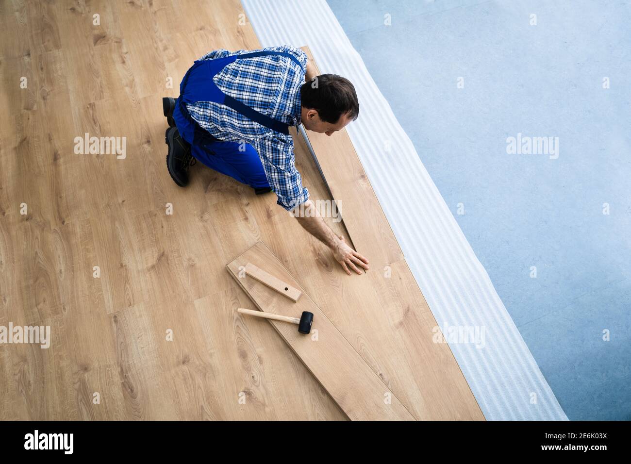 Ristrutturazione del pavimento in legno duro. Addetti alla costruzione che eseguono l'installazione di nuovi laminati Foto Stock