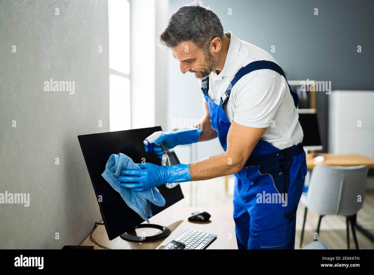 Servizio di pulizia professionale per ufficio Janitor. Monitor alla scrivania Foto Stock