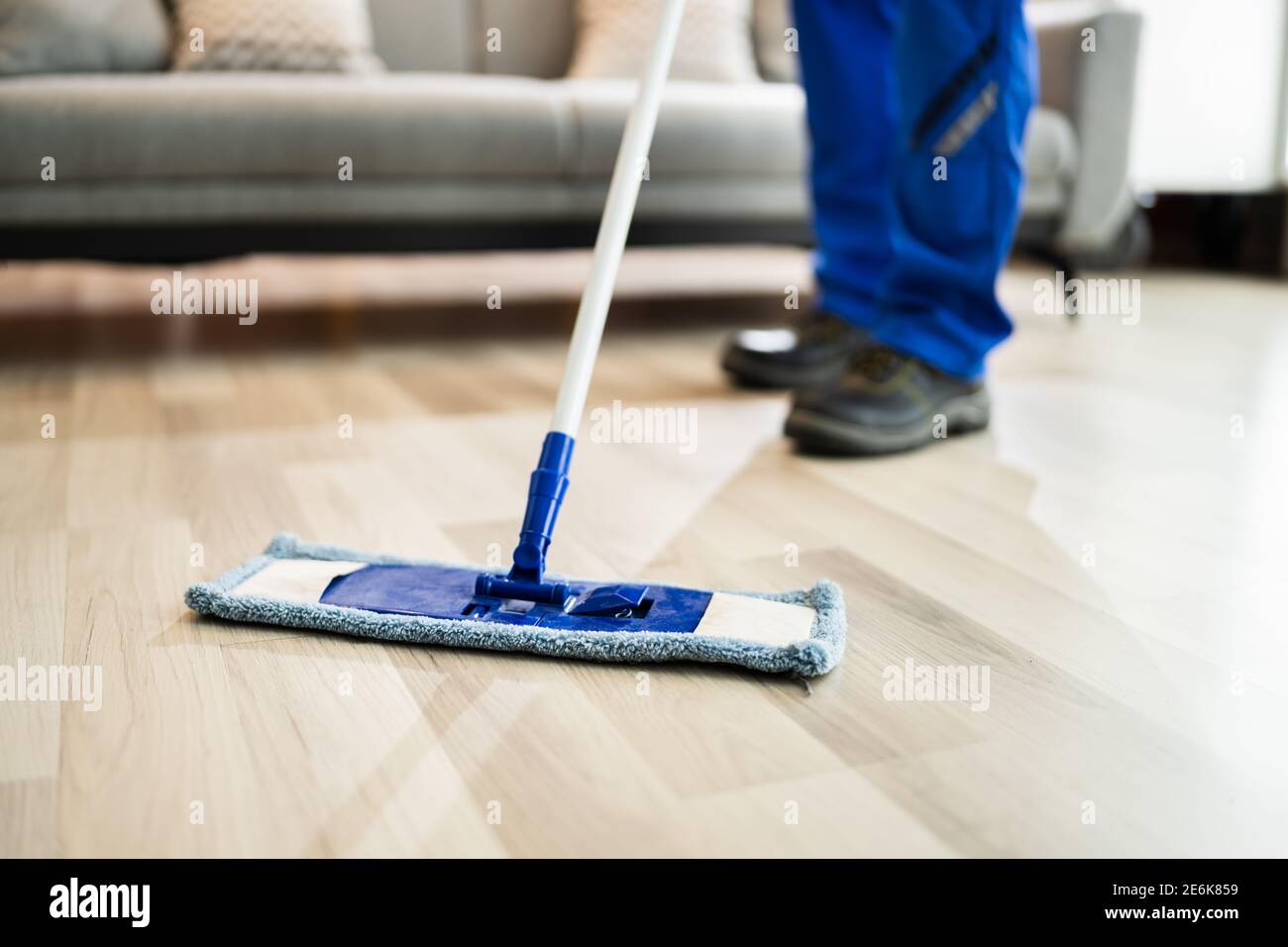 Servizio di pulizia del pavimento domestico. Soggiorno uomo Mopping Foto Stock