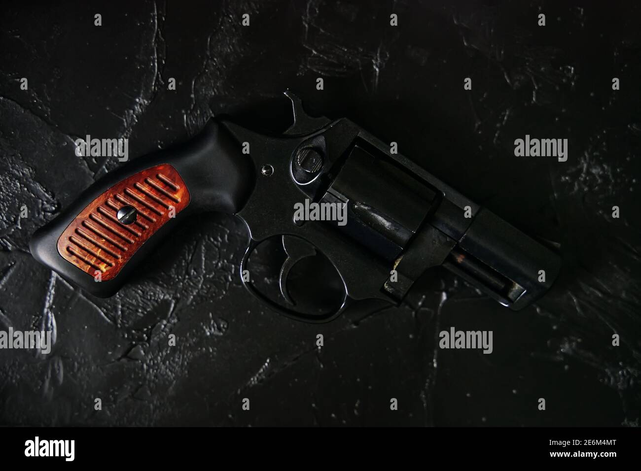 Pistola vintage su tavolo in cemento testurizzato. Revolver con manico in legno e tamburo. Armi da fuoco su sfondo nero. Vista dall'alto della pistola retrò. Foto Stock