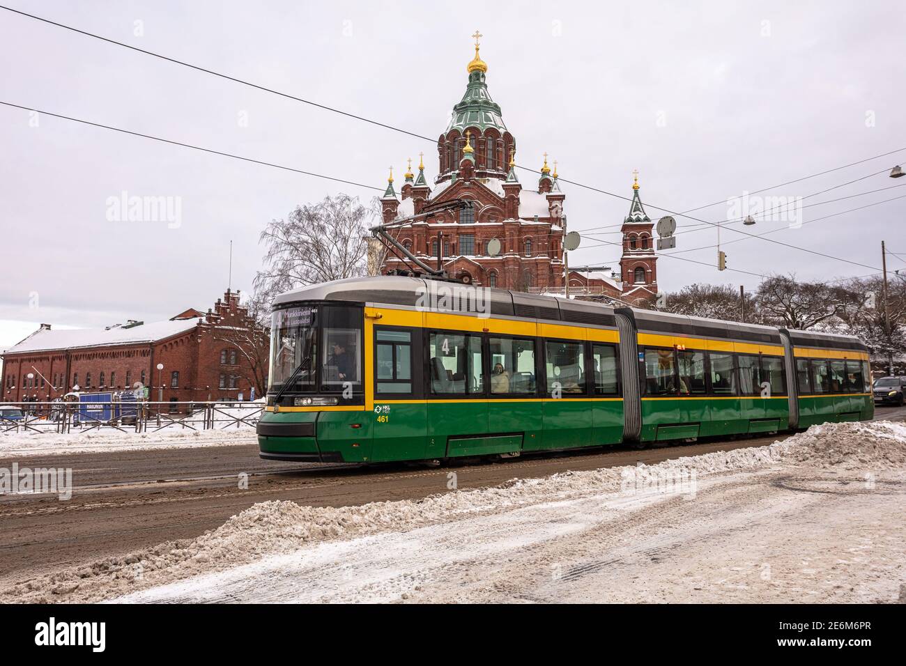 Helsinki. Finlandia. 19 gennaio 2021 Snowy Helsinki. Tram moderno su una strada innevata d'inverno. Vecchie facciate colorate di edifici sulla strada coperta di neve in inverno in città. Concetto di trasporto. Contrasto tra vecchio e nuovo. Foto di alta qualità Foto Stock