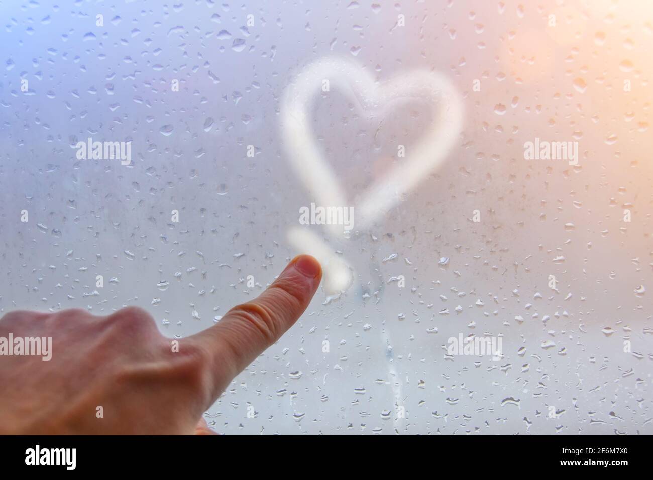Una mano e un dito attirano un cuore sul vetro appannato, la sensualità, l'amore per i cari, l'anima gemella Foto Stock