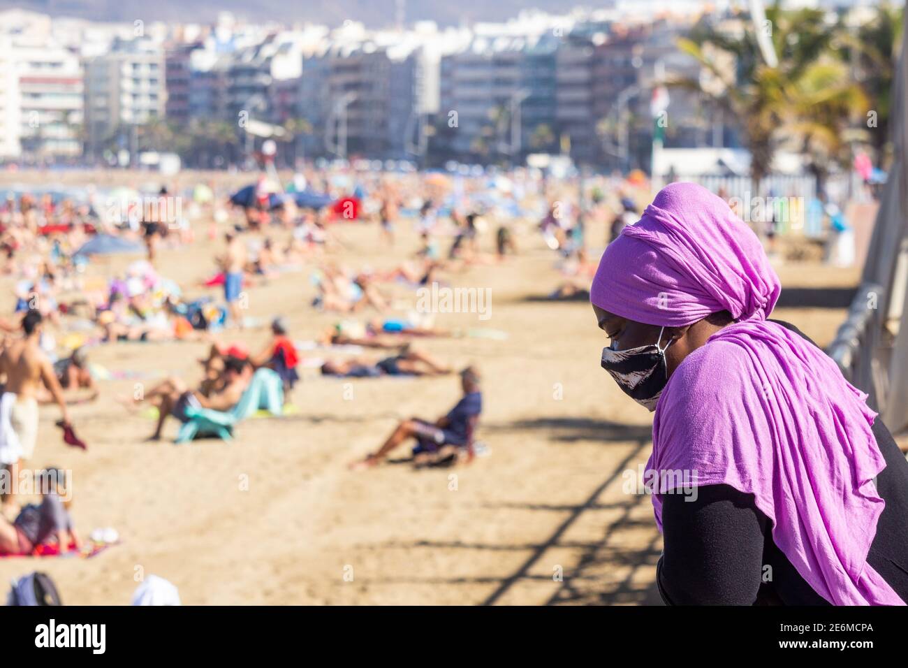 Donna nera che indossa la maschera/copertura che si affaccia sulla spiaggia Spagna Foto Stock