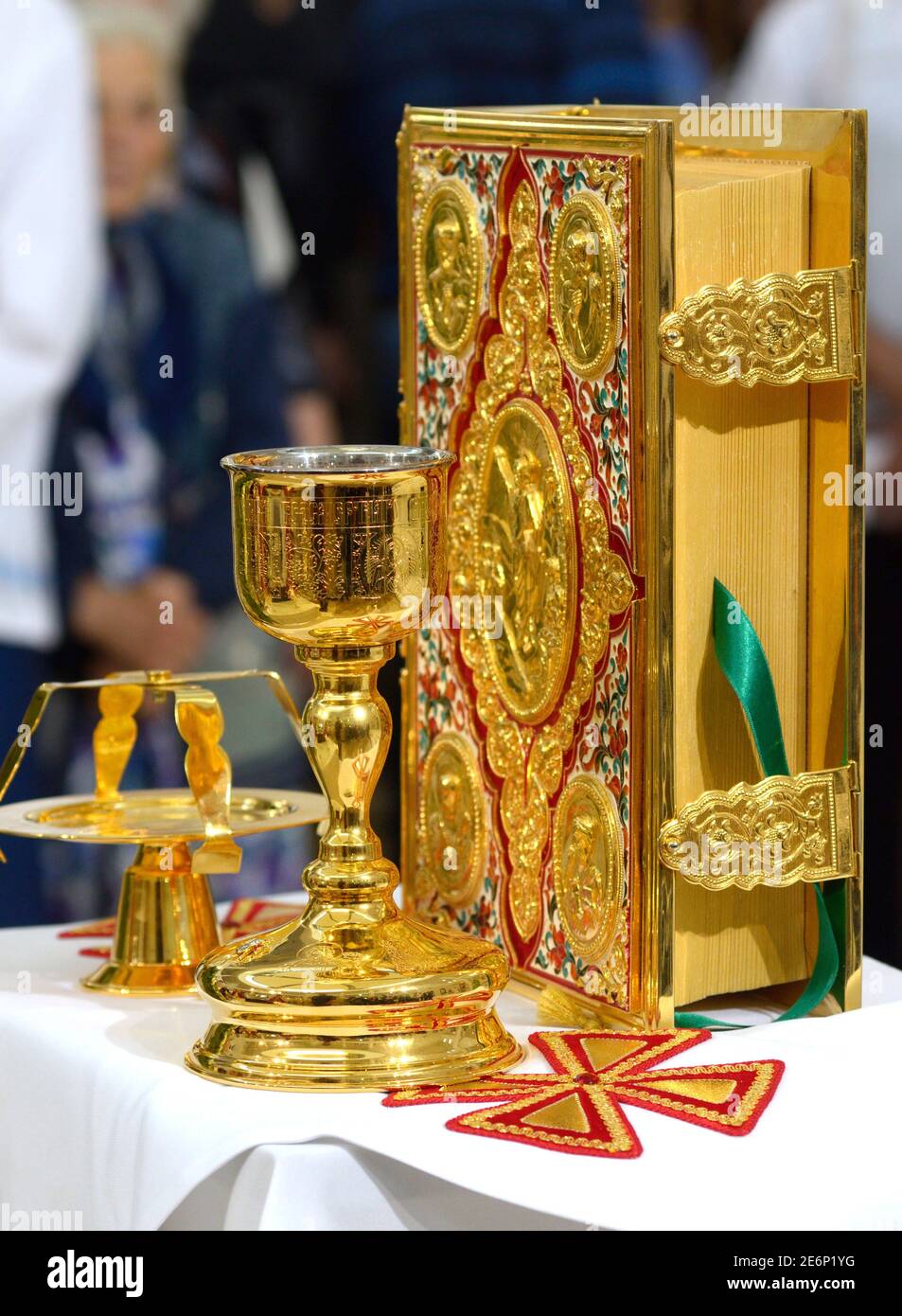 Sacra Bibbia in copertina dorata, coppa d'oro e portacandele posti su un tavolo durante il servizio della chiesa Foto Stock