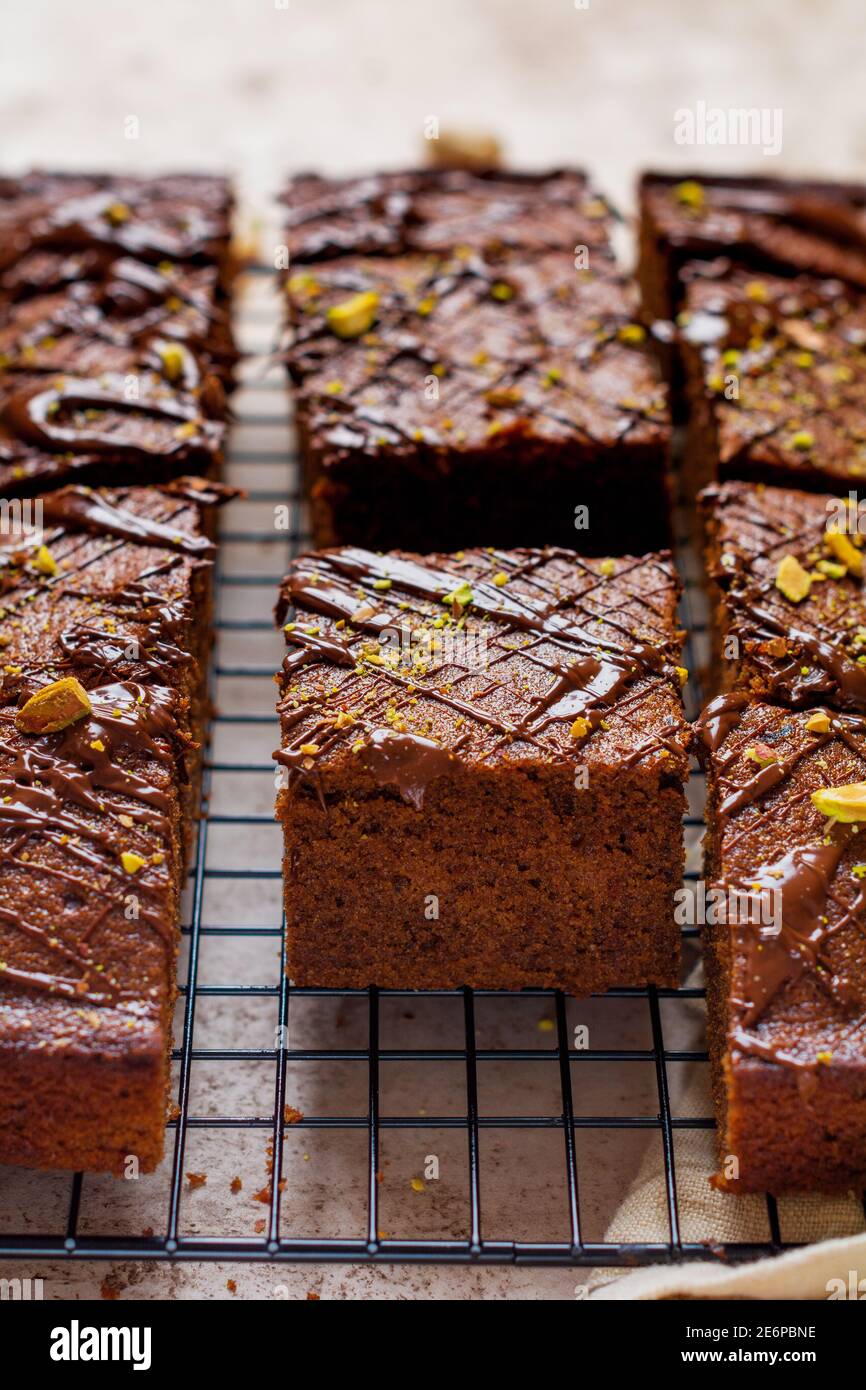 Quadrati di cioccolato con pistacchio e fragole su carta bianca su sfondo chiaro, vista dall'alto, composizione orizzontale. Cibo piatto. Foto Stock