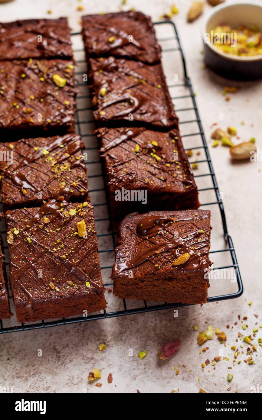 Quadrati di cioccolato con pistacchio e fragole su carta bianca su sfondo chiaro, vista dall'alto, composizione orizzontale. Cibo piatto. Foto Stock