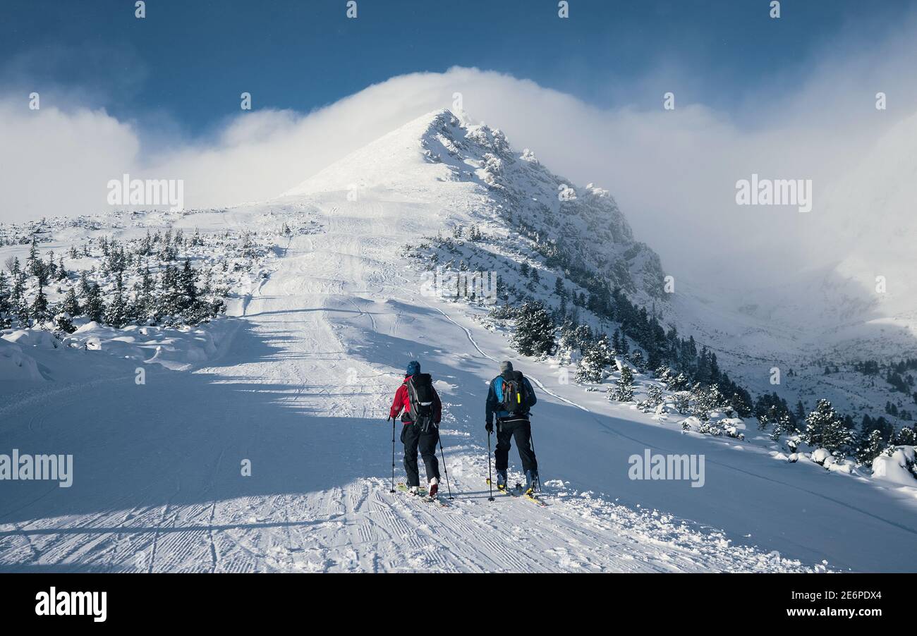 Gruppo di sci di fondo coppia di uomo e donna verso la cima della montagna. Gruppo di alpinisti si sono arrampicati in cima in inverno. Foto Stock