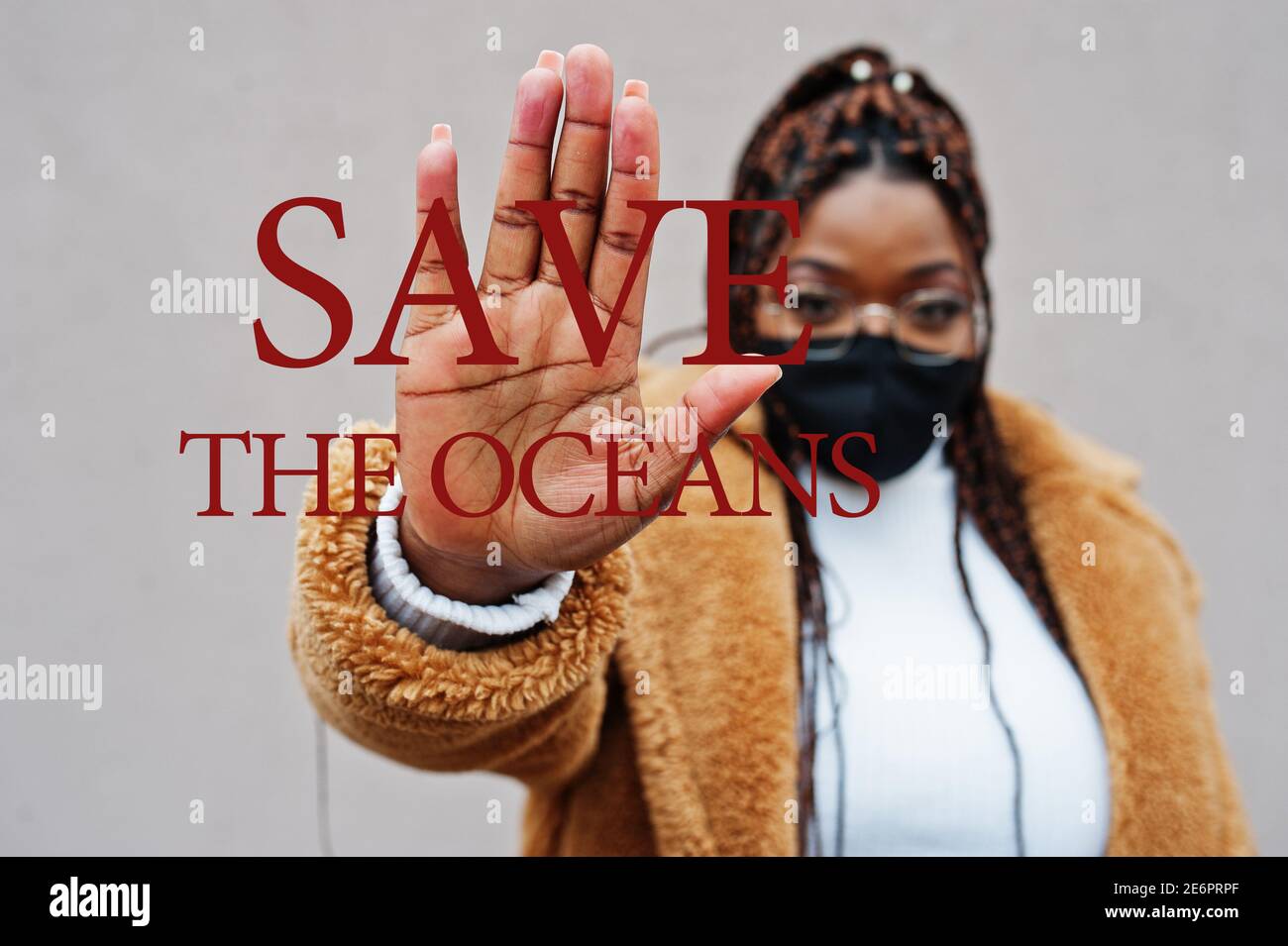 Salvare gli oceani. Donna afroamericana, indossare maschera nera mostra segno di stop mano. Foto Stock