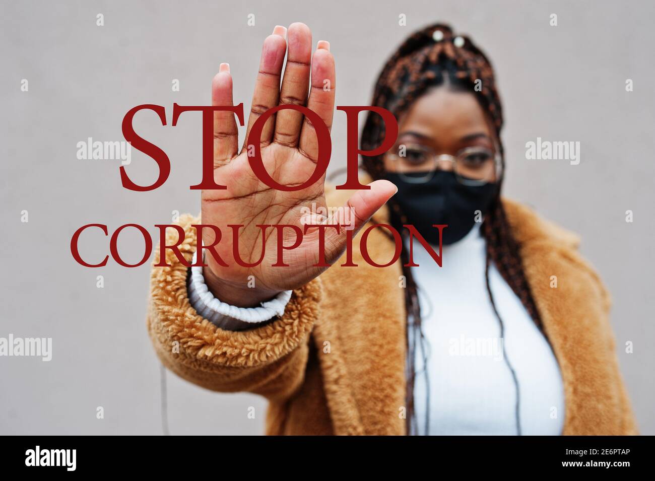 Fermare la corruzione. Donna afroamericana, indossare maschera nera mostra segno di stop mano. Foto Stock