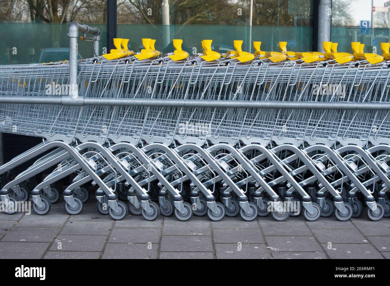 Una fila di carrelli per lo shopping in argento e giallo a supermercato Foto Stock