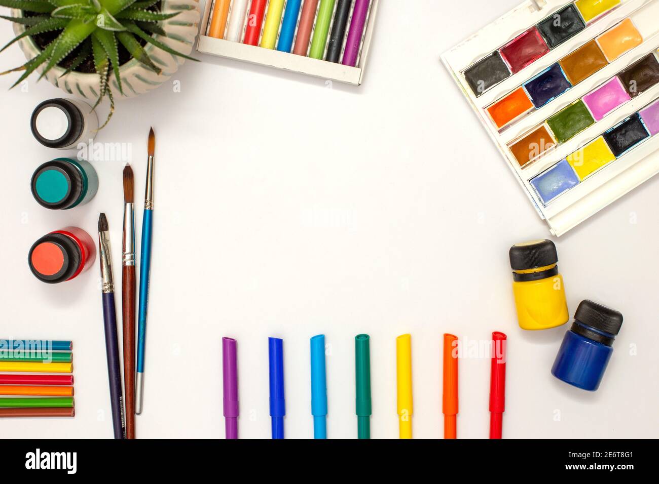 tavola bianca, forniture per disegno: acquerello, pastelli pastello, pennarelli colorati, pennelli, vernici acriliche, pentola succulente. Foto Stock