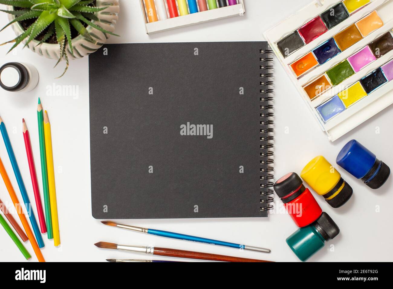 Libro di schizzo nero su una tabella bianca con materiali di disegno. Foto Stock
