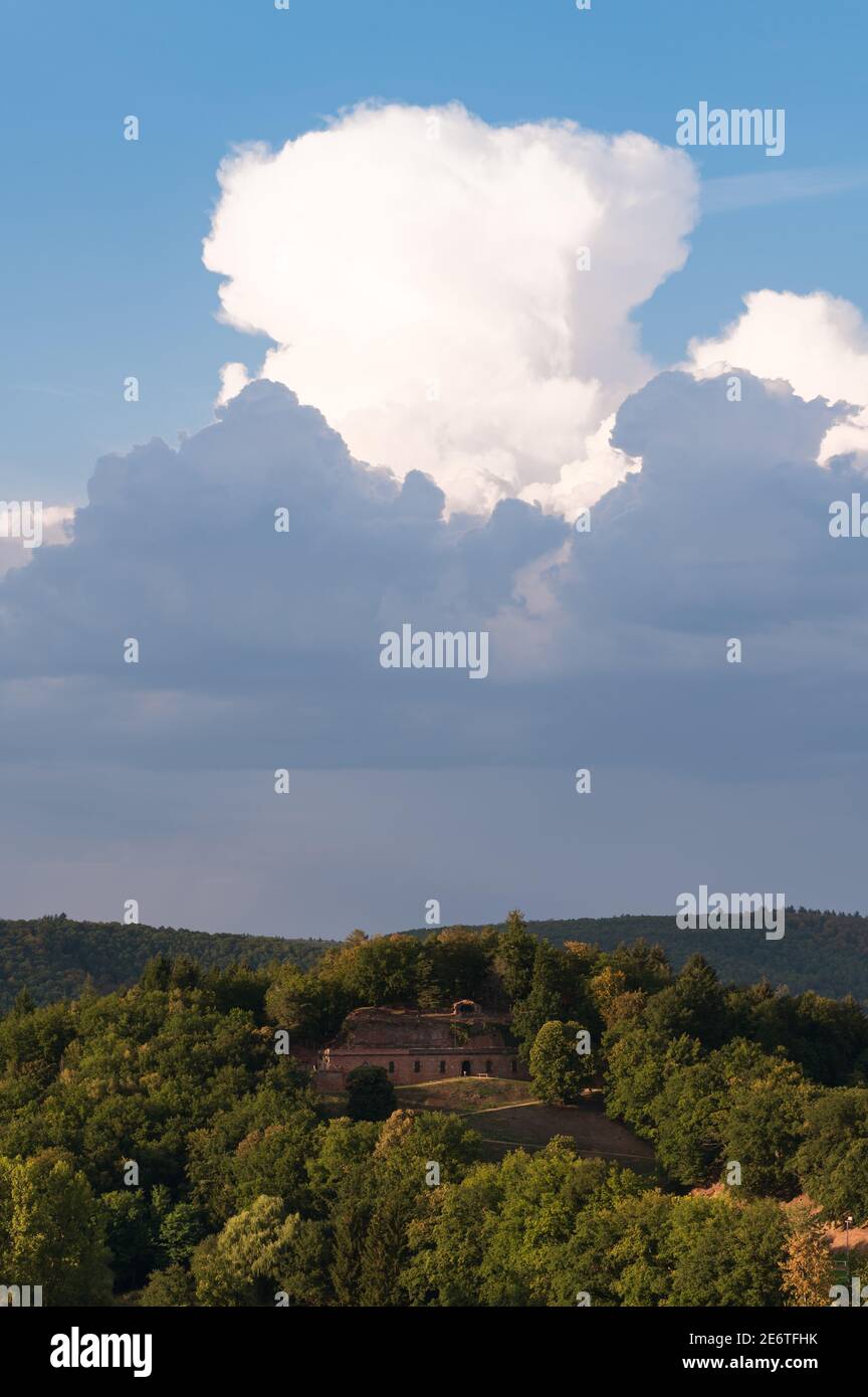Fort Saint Sebastien è impacchettato nella vegetazione abbondante del villaggio di Bitche coronato da una grande nuvola di Cumulus Nimbus. Foto Stock