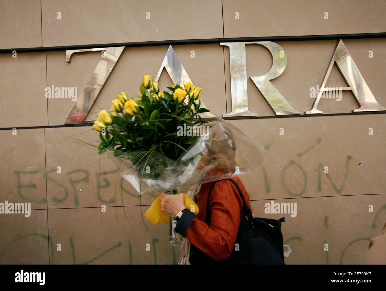 Una donna che tiene un mazzo di fiori cammina fuori da un negozio Zara nel  centro di Siviglia 25 marzo 2009. La Inditex SA, il più grande rivenditore  di abbigliamento europeo, prevede