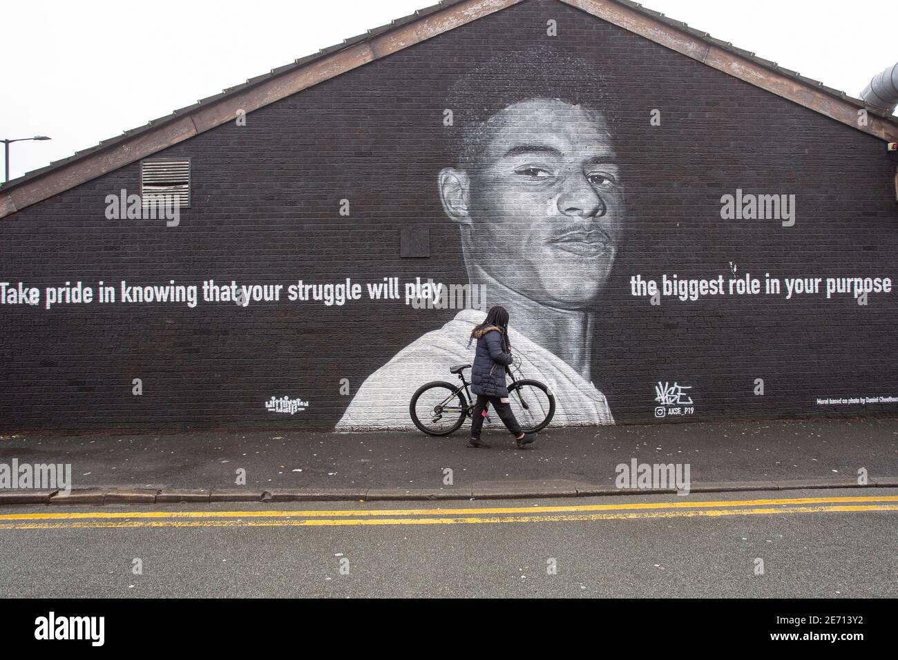 Il bambino nero sta passando il murale del giocatore di calcio del Manchester United Marcus Rashford sul lato di un edificio a Withington, Manchester, nord-ovest E. Foto Stock