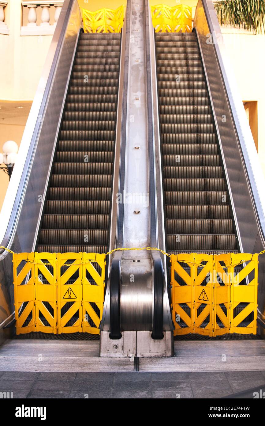 ascensore fuori servizio con due recinzioni gialle. Scala mobile rotta con segnali di avvertimento. Foto Stock