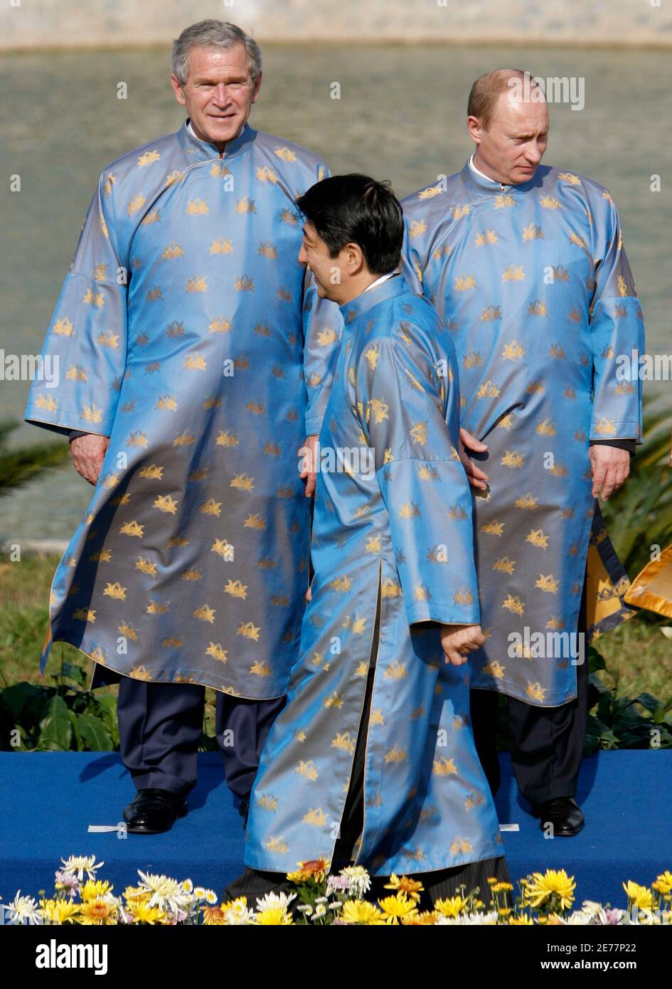 Japan's Prime Minister Shinzo Abe walks in front of U.S. President George W. Bush (L) and Russian President Vladimir Putin, wearing traditional Vietnamese clothes, known as the "ao dai", during the official photograph for the the Asia-Pacific Economic Cooperation (APEC) Summit in Hanoi, November 19, 2006. REUTERS/Jim Young (VIETNAM) Foto Stock