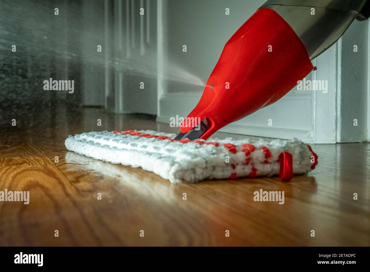 Un mop a getto spray per la pulizia di pavimenti in legno duro in azione. Foto Stock