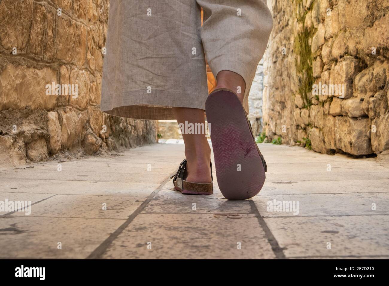 Foto dettagliata delle gambe femminili indossando comodi sandali da viaggio a piedi su vecchie strade di ciottoli medievali che drappeggiano il tour panoramico della città. Viaggi, turismo Foto Stock
