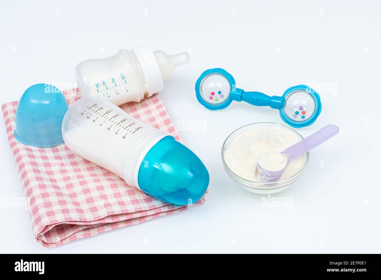 Accessori per l'allattamento - biberon su tessuto, cucchiaio con formula e beanbag. Set di diversi accessori per bambini sul tavolo bianco Foto Stock