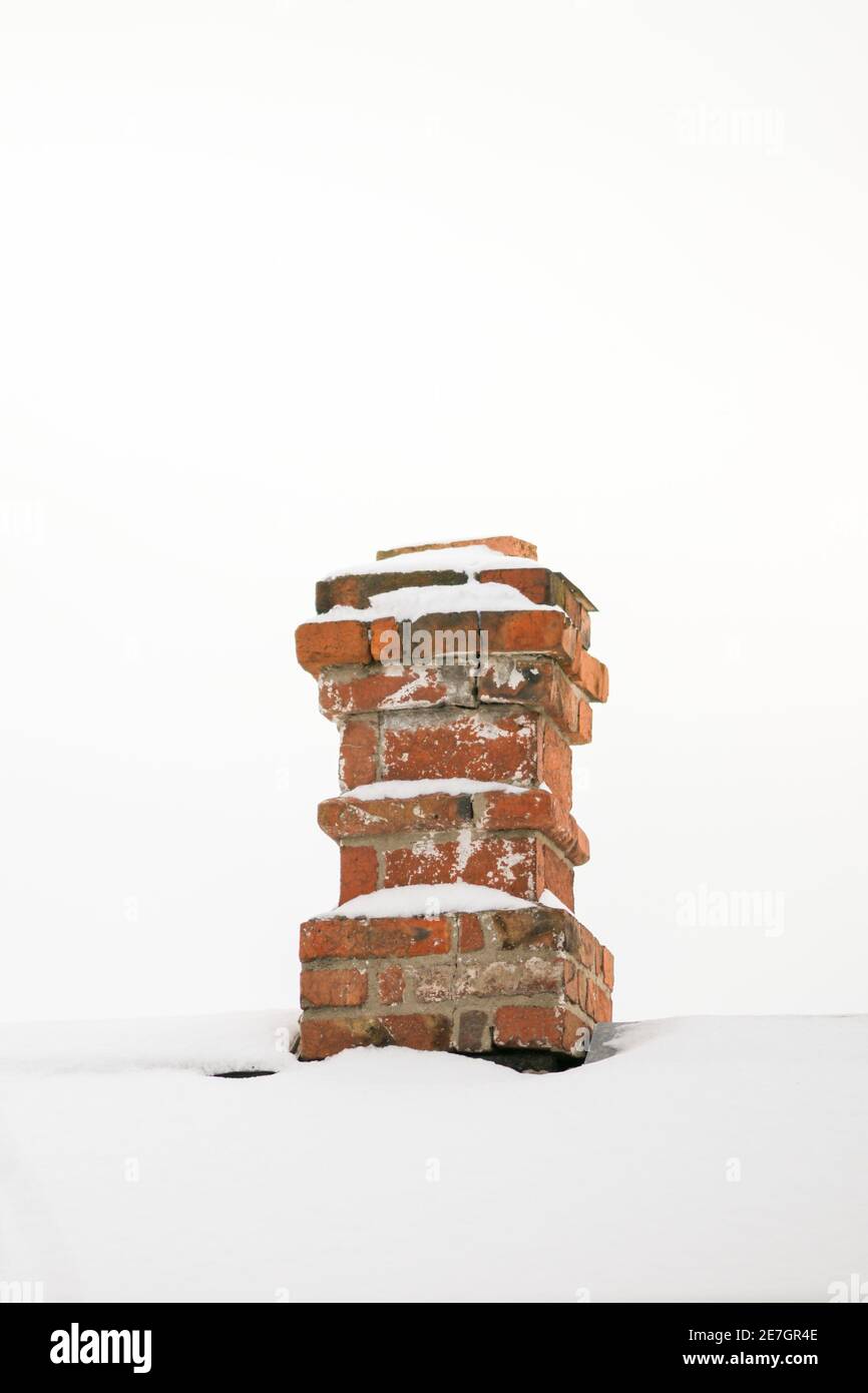 Vecchio camino in mattoni rossi con neve bianca e cielo. Foto Stock