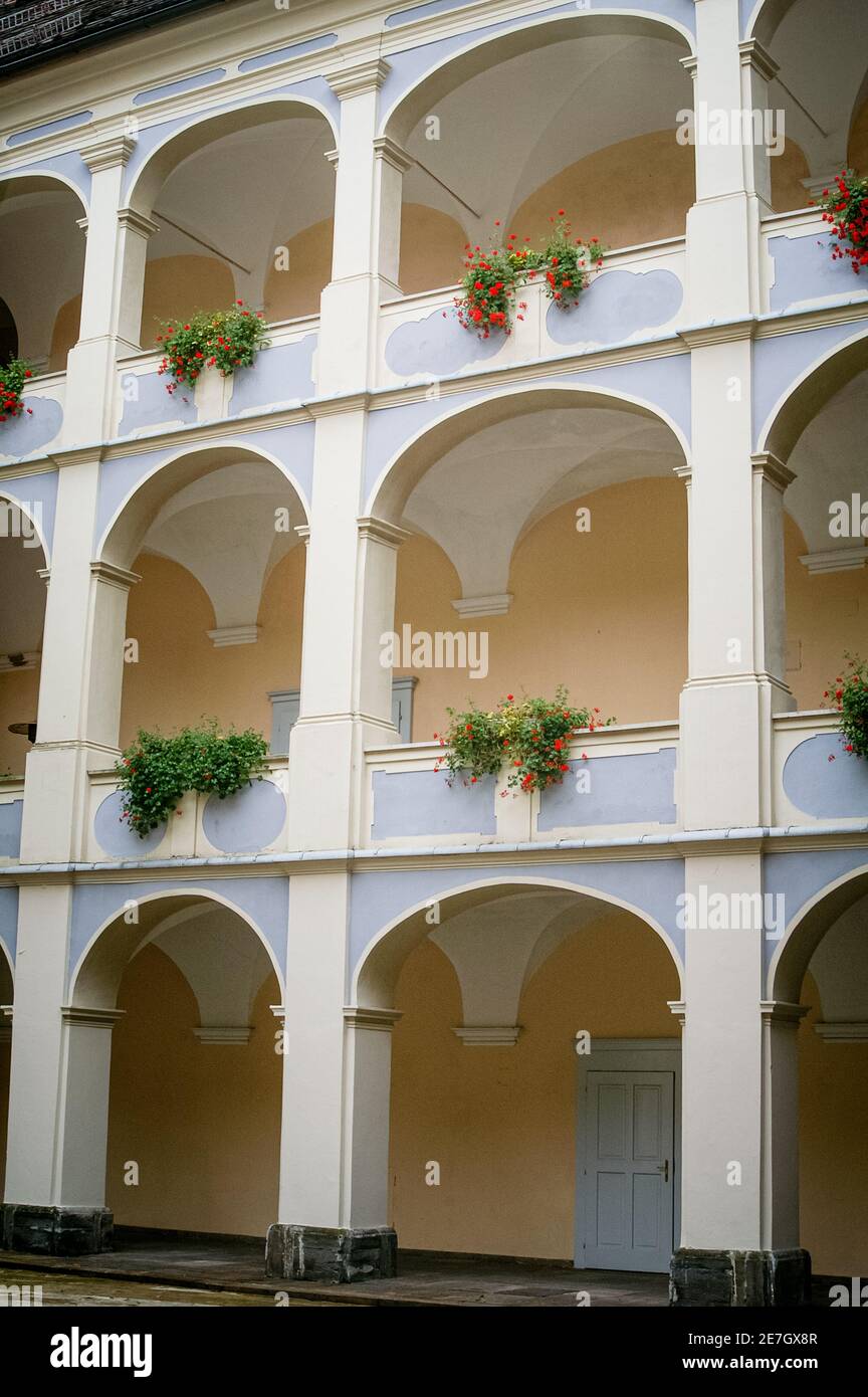 Edificio storico a tre piani con archi classici e cesti di fiori appesi Foto Stock